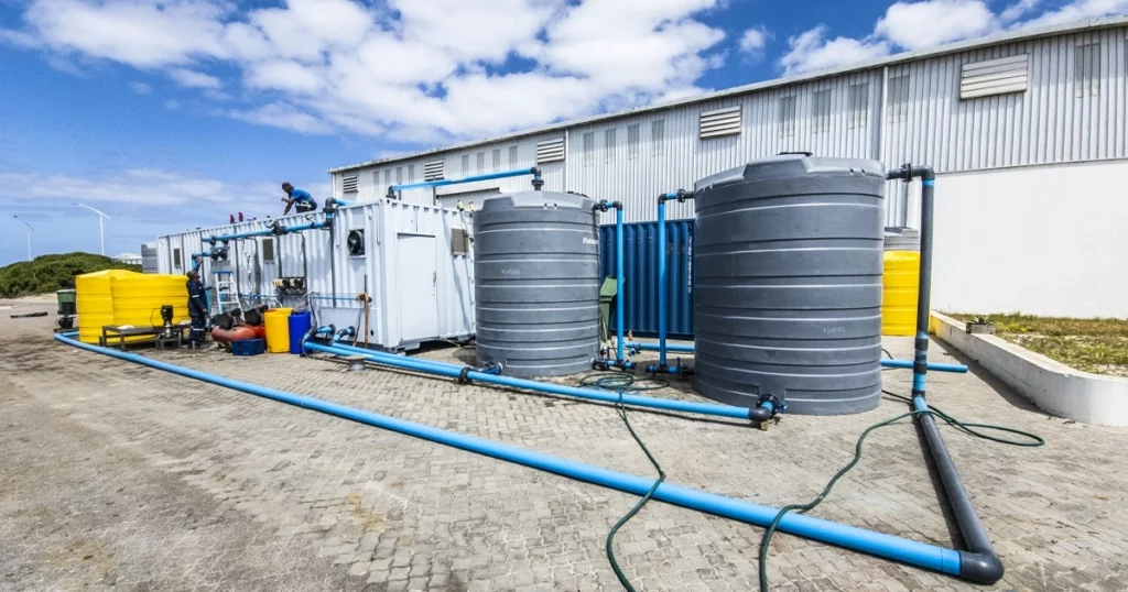 A Containerized Water Treatment Plant With Associated Storage Tanks And Piping, Showcasing Nuwater'S Comprehensive Solution.