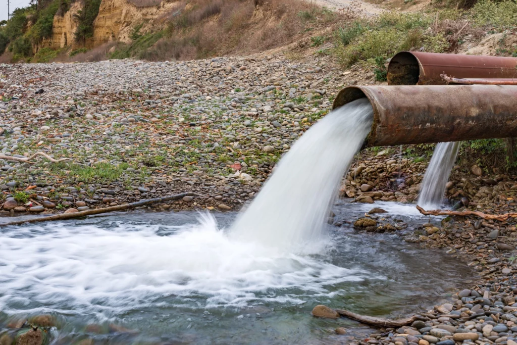 Raw Wastewater Being Discharged Into A Waterway, Illustrating The Dangers Of Untreated Water In Water-Scarce Regions.