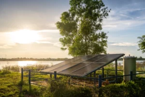 Solar Panels Powering A Water Pump Near A Reservoir.
