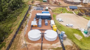 An Expansive Aerial View Showcasing The Full Layout Of Nuwater'S Rapidly Deployed Ultrafiltration Water Treatment Plant, Including Large Circular Storage Tanks, Modular Blue Treatment Units, And Interconnected Piping.