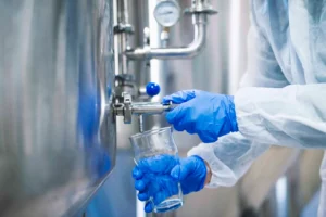 Operator In Gloves Sampling Water From An Industrial Tank, Showcasing Sustainable Water Treatment.
